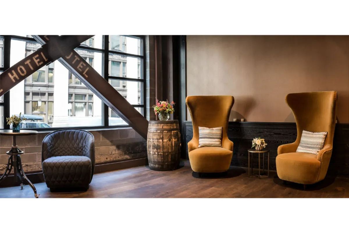This image features two elegant armchairs set around a barrel table, complemented by a decorative flower arrangement. The cozy seating area is bathed in warm lighting, creating an inviting space ideal for relaxation, reading, or quiet moments of comfort.