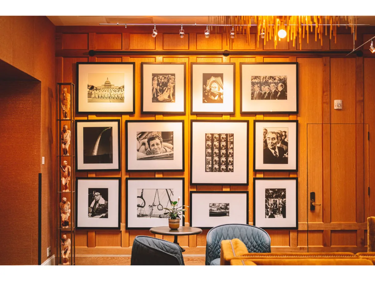 A contemplative area with a gallery wall featuring numerous framed photographs, modern furniture, and an indoor plant. The mood is creative and introspective, inviting guests to pause and appreciate the stories behind each piece.
